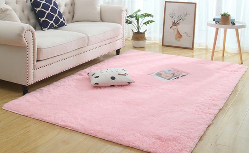 tapis rose dans un salon près d'un canapé blanc