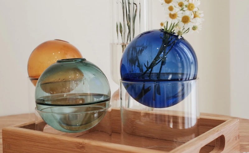trois jolis vase boule disposés sur un plateau en bois