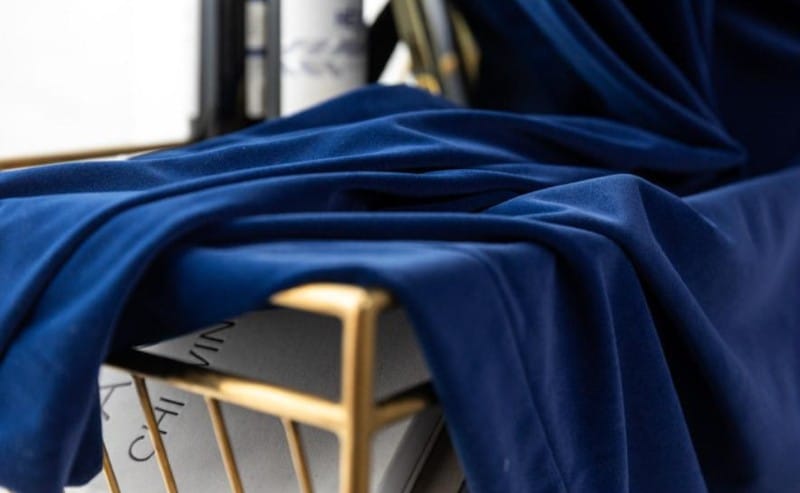 une paire de rideau velours bleu foncé posé sur un tabouret