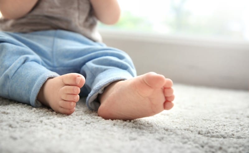 un petit bébé assis sur un tapis beige